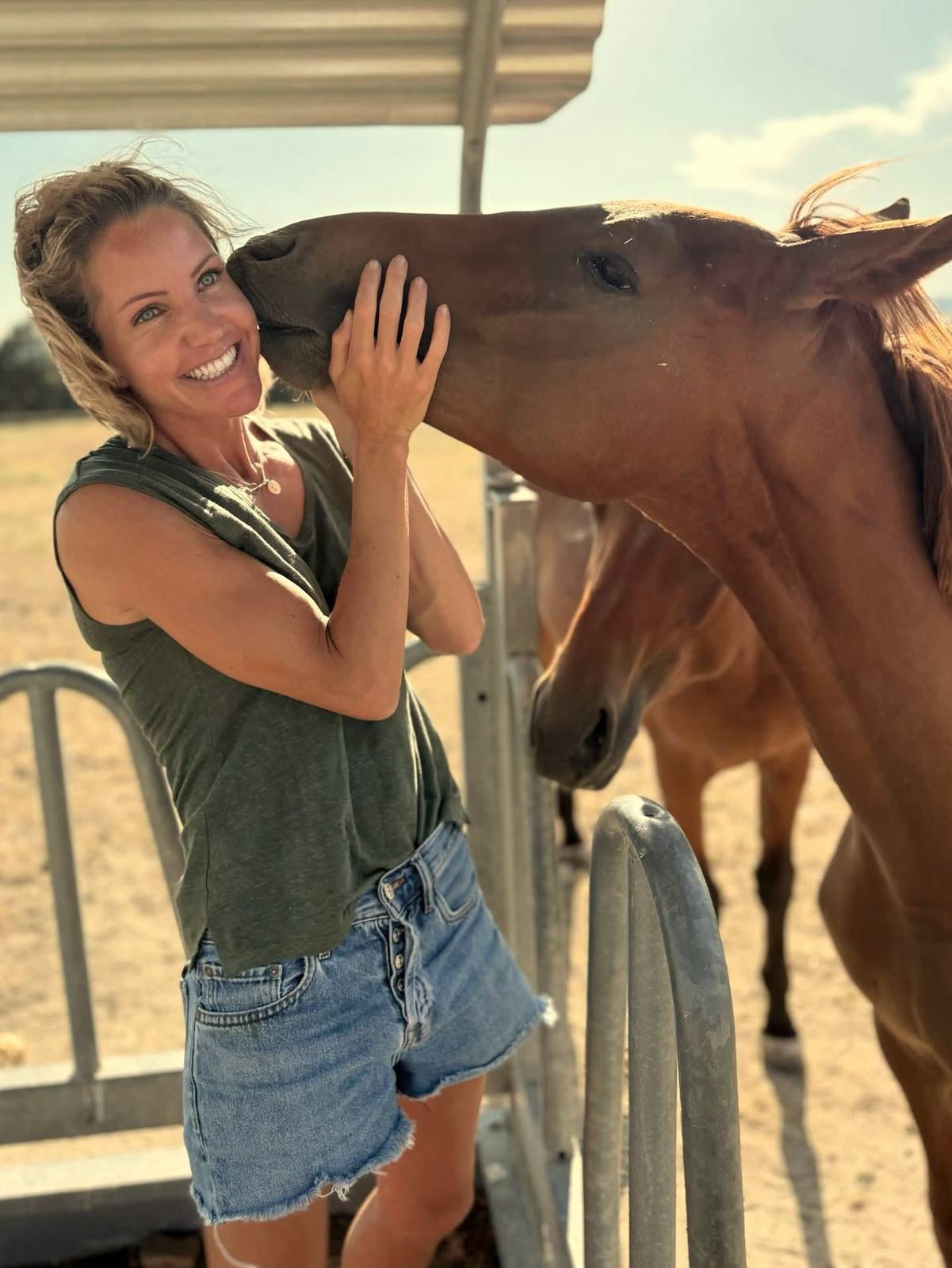Diana sonriendo con un caballo alazán en el campo