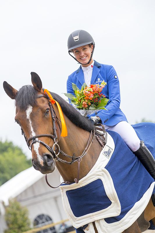 Diana sonriendo a caballo con un ramo de flores tras un premio